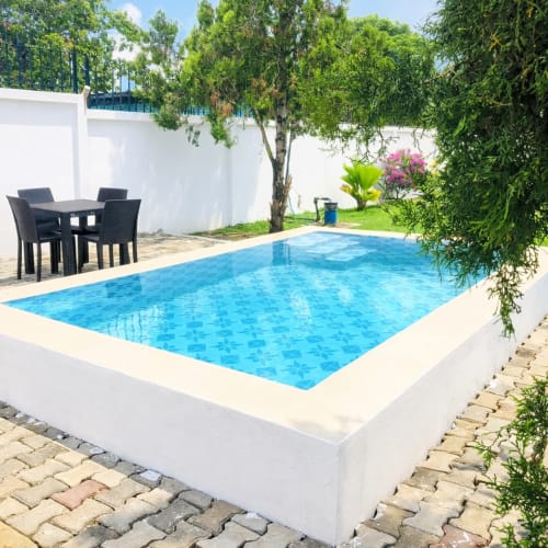 Piscine rectangulaire aux eaux bleues dans un jardin luxuriant de La Villa des Pins, Libreville