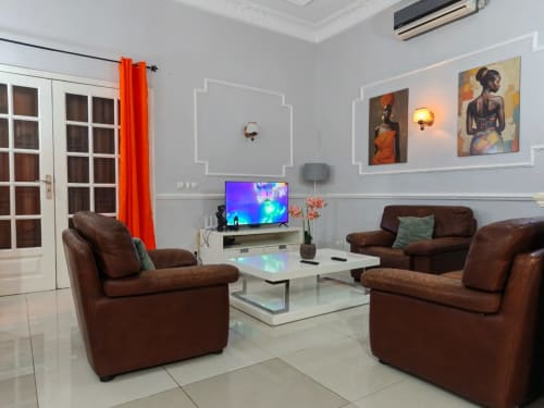 Salon moderne de La Villa des Pins, Libreville avec sièges en cuir marron, téléviseur et œuvres d'art africaines