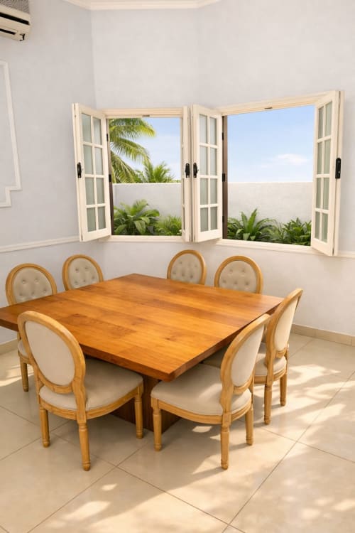 Salle à manger de La Villa des Pins avec table en bois, chaises couleur crème et vue sur le jardin par les portes-fenêtres ouvertes à Libreville