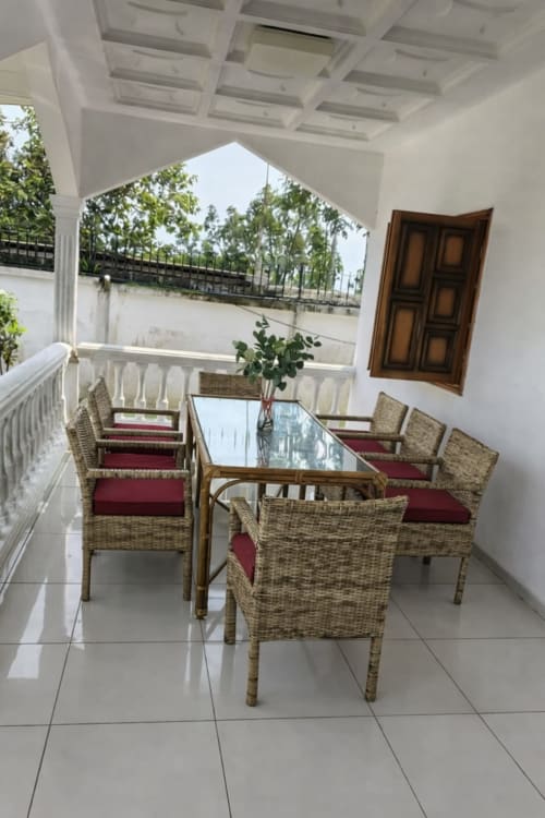 Terrasse couverte avec fauteuils en rotin et coussins rouges à La Villa des Pins, Libreville
