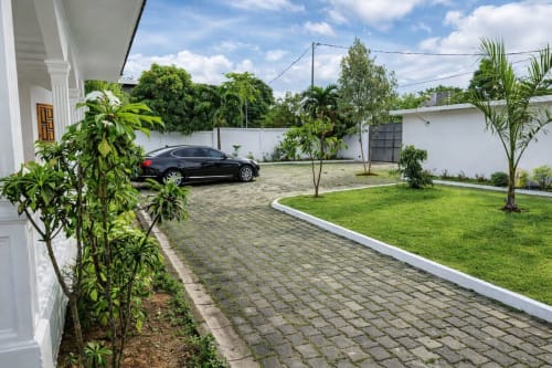 La Villa des Pins à Libreville avec jardin soigné, allée pavée et voiture garée