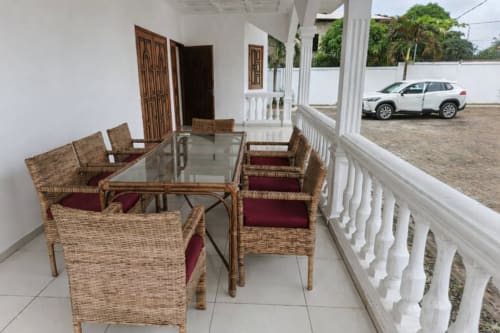 Véranda couverte avec fauteuils en rotin à La Villa des Pins à Libreville, vue sur le jardin