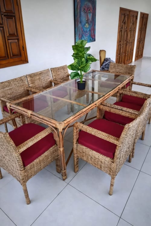Ensemble de salle à manger tressé avec table en verre et coussins bordeaux à La Villa des Pins, Libreville