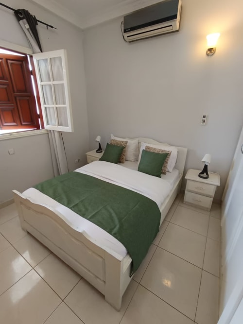 Chambre moderne à La Villa des Pins à Libreville avec lit queen-size, accents verts et climatisation