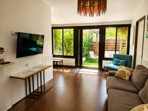 Moderno salón de casa de campo con vista al jardín, asientos cómodos, televisor de pantalla plana y acceso a patio en Péret, Francia