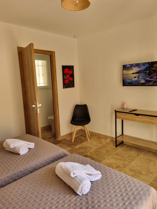 Chambre moderne à L'Orée du Ventoux B&B à Crillon-le-Brave avec lits jumeaux, mobilier en bois et accès à la salle de bain