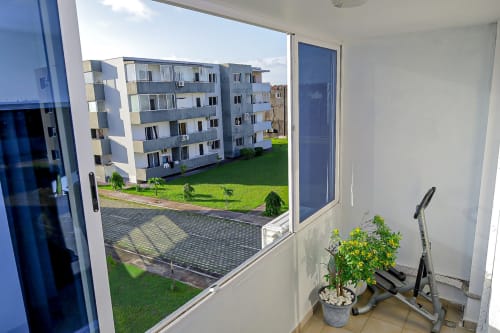 Vue depuis le balcon de l'appartement La Villa des Pins à Libreville, avec cour-jardin, bâtiments résidentiels et équipements de fitness