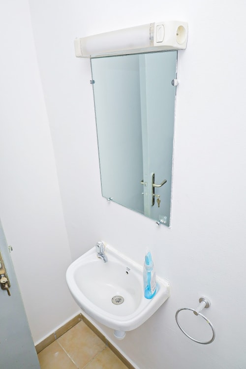 Lavabo blanc mural avec armoire miroir et porte-serviettes dans la salle de bain de l'appartement La Villa des Pins