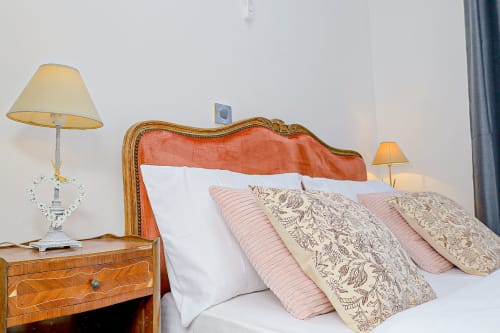 Chambre élégante à La Villa des Pins avec tête de lit ornée, coussins à motifs et lampe de chevet à la propriété Akanda