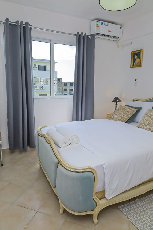 Chambre élégante avec lit raffiné, rideaux gris et climatisation à l'hôtel La Villa des Pins de Libreville, Gabon