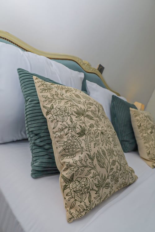 Oreillers décoratifs aux motifs botaniques vert et crème à l'appartement La Villa des Pins de Libreville
