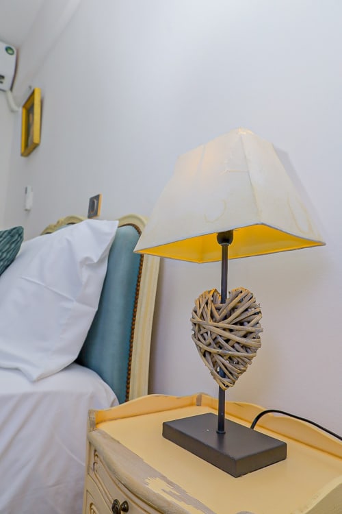 Lampe de table moderne à abat-jour jaune et base en rotin tressé sur la table de nuit, appartement La Villa des Pins