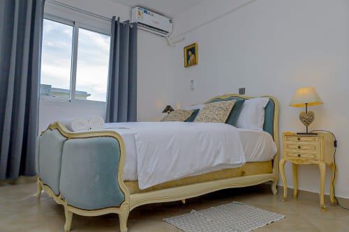 Suite élégante à La Villa des Pins avec lit à la française crème et or, accents bleu-vert, vue sur jardin à Libreville