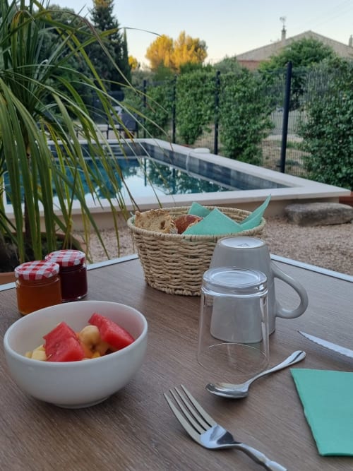 Table de petit-déjeuner avec vue sur la piscine à L'Orée du Ventoux, Crillon-le-Brave, fruits frais et pâtisseries