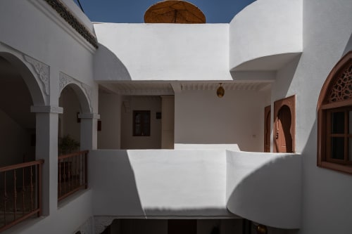 Cour du Riad Dabachi Tala'lou à Marrakech : murs blancs, portes arquées, portes en bois et ciel bleu