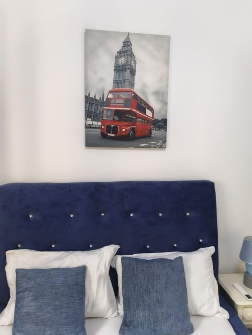 Affiche du bus rouge londonien à deux étages avec Big Ben au-dessus d'un lit aux tissus bleus à La Villa des Pins