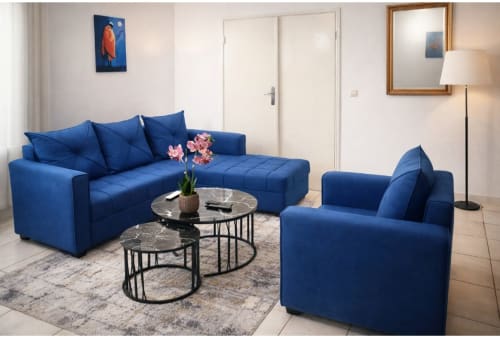 Élégant salon moderne bleu à La Villa des Pins à Akanda avec canapé, fauteuil et tables en marbre