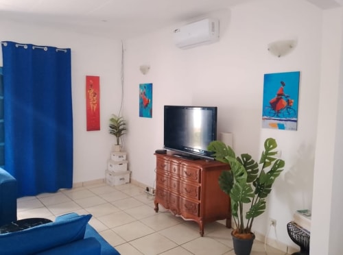 Chambre moderne de la Villa des Pins, Akanda : téléviseur, commode en bois, plantes en pot, art mural coloré et bleu