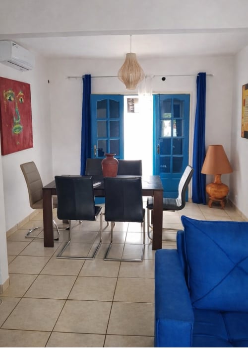 Espace de vie moderne à la villa La Villa des Pins à Akanda avec portes bleues, table à manger et canapé bleu