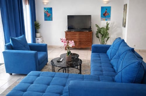 Salon moderne de la villa La Villa des Pins à Akanda avec mobilier bleu, télévision et décoration élégante