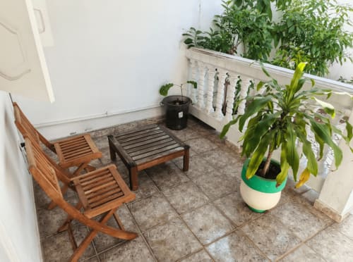 Patio couvert de La Villa des Pins avec chaises longues en bois, table et plantes en pot à Akanda