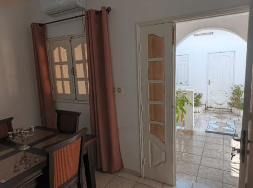 La Villa des Pins à Akanda, porte ouverte sur la cour, mobilier en bois, rideaux couleur rouille
