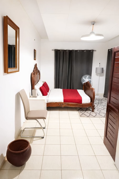 Chambre spacieuse de La Villa des Pins à Akanda avec lit en bois, literie rouge et équipements modernes