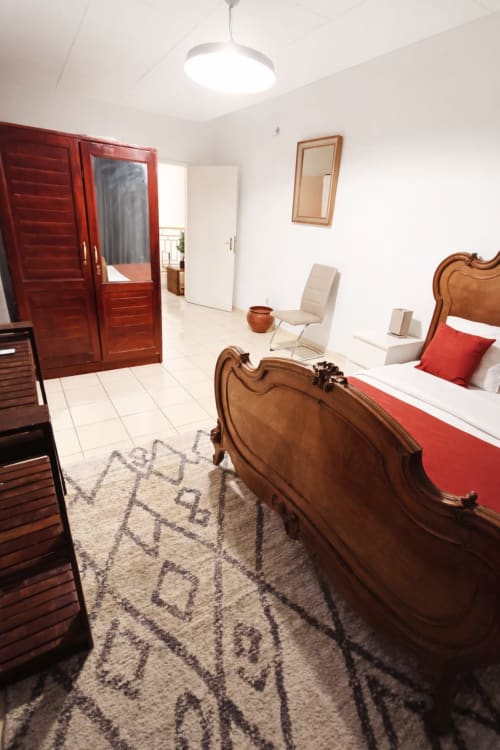 Chambre spacieuse à La Villa des Pins à Akanda avec lit en bois, accents rouges et équipements modernes