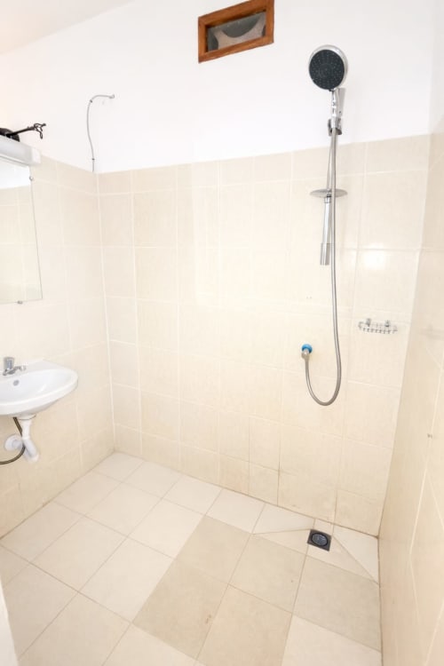 Salle de bains moderne avec carrelage beige, pommeau de douche manuel et lavabo sur piédestal à La Villa des Pins