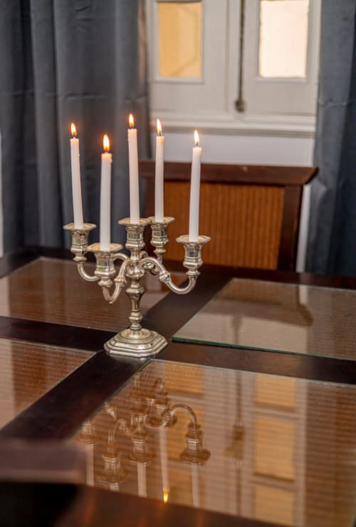 Candélabre en argent avec des bougies blanches allumées sur une table en bois poli à La Villa des Pins à Akanda