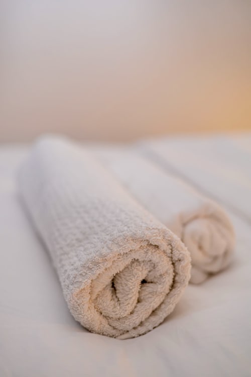 Serviettes beiges roulées à La Villa des Pins, mettant en avant des linges de luxe et les équipements de salle de bain