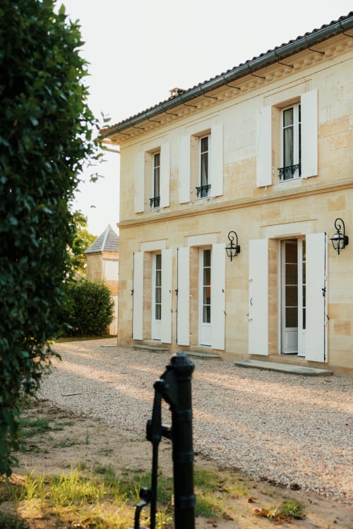 Elegant stone façade of Château Alto Cormeil B&B in Saint-Émilion with white shuttered windows and gravel courtyard