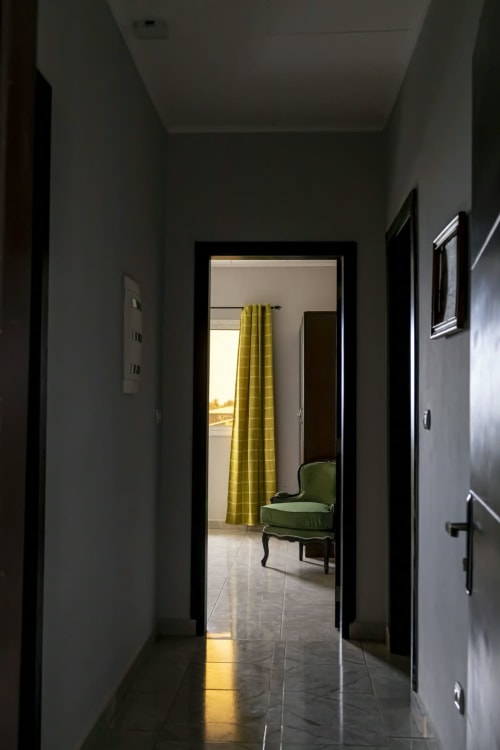 Couloir moderne de La Villa des Pins, Akanda, menant à un appartement meublé avec vue mer et rideaux jaunes
