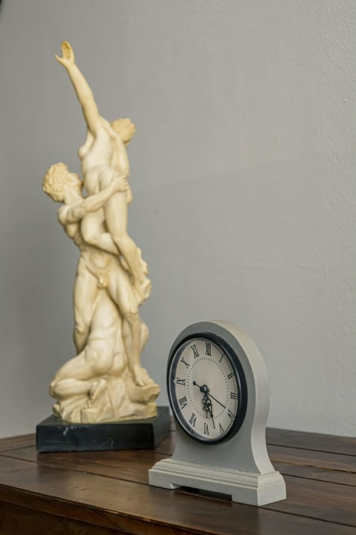 Statue sculptée en ivoire et horloge de bureau blanche sur surface en bois à La Villa des Pins, Akanda