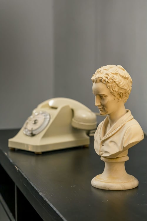Buste en terre cuite et téléphone rotatif vintage sur table noire à l'appartement de la marina La Villa des Pins