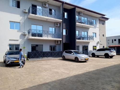 Immeuble résidentiel moderne La Villa des Pins avec voitures garées à Akanda, Gabon, offrant balcons et vue mer