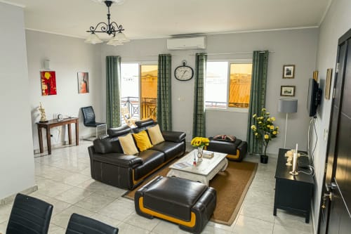 Salon moderne à La Villa des Pins Marina à Akanda : canapé en cuir noir, accents jaunes, balcon avec vue mer
