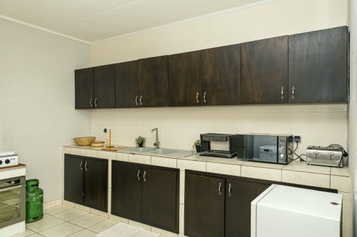 Cuisine aux armoires foncées dans l'appartement Marina de La Villa des Pins à Akanda, avec plans de travail et électroménagers crème