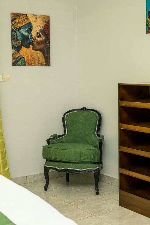Fauteuil en velours vert avec structure noire dans l'appartement La Villa des Pins à Akanda. Décoration murale inspirée de l'Égypte ancienne au-dessus.