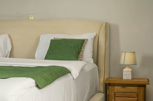 Chambre à La Villa des Pins Marina à Akanda avec accents verts, literie blanche et table de nuit en bois avec lampe