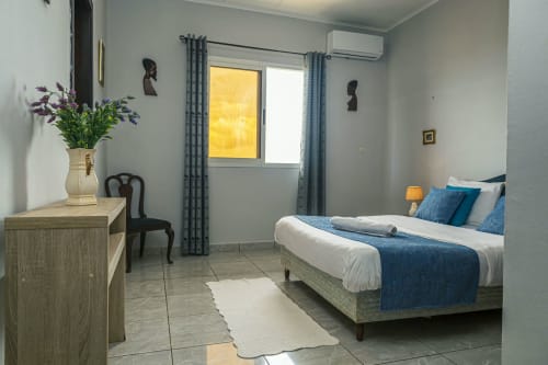 Chambre moderne à La Villa des Pins, Akanda avec literie bleue, mobilier en bois et vue sur mer