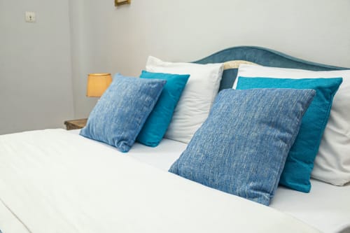 Chambre moderne à La Villa des Pins avec tête de lit capitonnée bleu-vert, literie blanche et décoration à motifs bleus