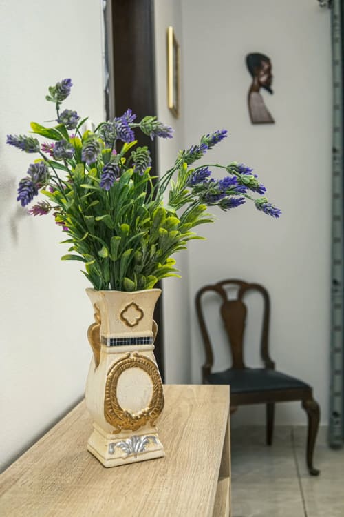 Vase élégant en bois avec fleurs violettes sur table à La Villa des Pins, appartement marina d'Akanda, chaise et art mural