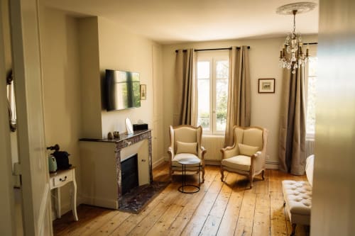 Chambre élégante du Château Alto Cormeil à Saint-Émilion, avec cheminée, fauteuils, lustre et parquets