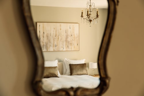 Chambre élégante du Château Alto Cormeil à Saint-Émilion avec literie blanche, coussins dorés et reflet de lustre en cristal