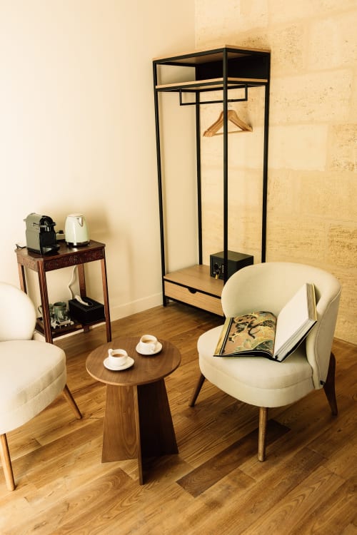 Chambre d'hôtel moderne au Château Alto Cormeil à Saint-Émilion avec décoration épurée, fauteuil crème et table d'appoint en bois