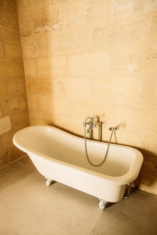 Baignoire îlot aux fixtures vintage dans la salle de bain en pierre du Château Alto Cormeil, Saint-Émilion