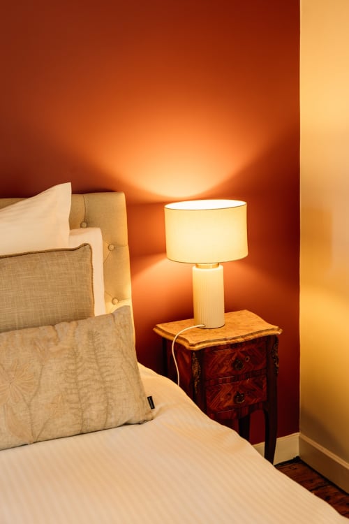 Chambre douillette au Château Alto Cormeil à Saint-Émilion avec lampe de chevet allumée et ambiance chaleureuse