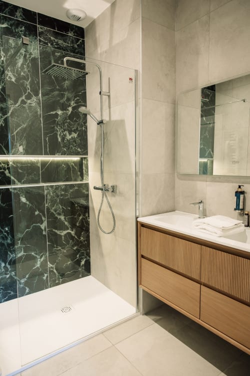 Baño moderno de la Chambre Malbec del Château Alto Cormeil con ducha de mármol, tocador de madera y espejos