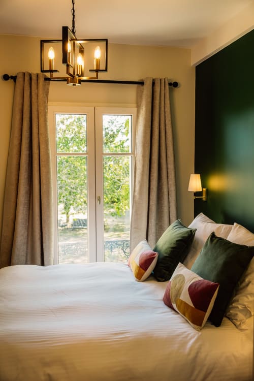 Elegante dormitorio en Château Alto Cormeil en Saint-Émilion con cama queen, pared de acento verde y puertas francesas con vistas